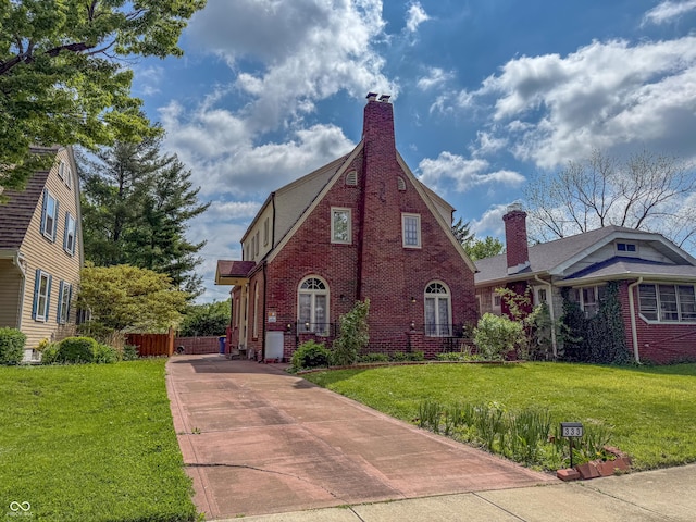 english style home with brick siding, concrete driveway, and a chimney