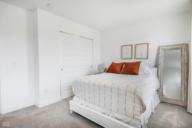carpeted bedroom with a closet and baseboards