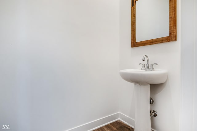 bathroom with wood finished floors, baseboards, and a sink