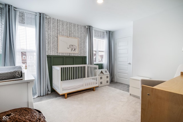 bedroom with a crib and light colored carpet