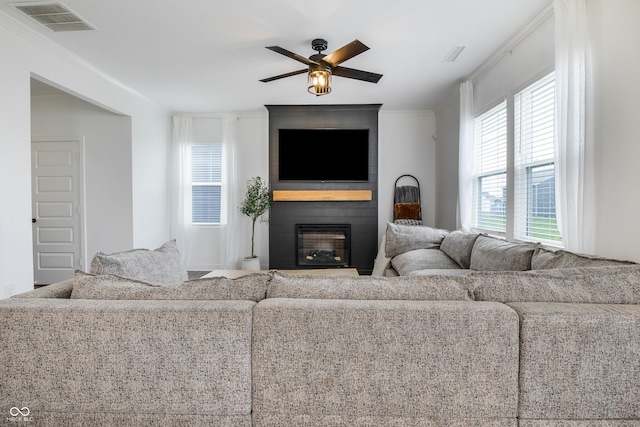 living room featuring ceiling fan, visible vents, and a large fireplace
