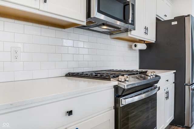 kitchen with light countertops, appliances with stainless steel finishes, decorative backsplash, and white cabinetry