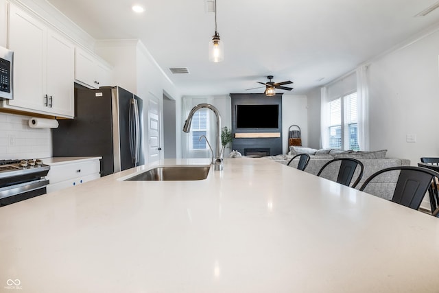 kitchen featuring a large fireplace, visible vents, ceiling fan, and a sink