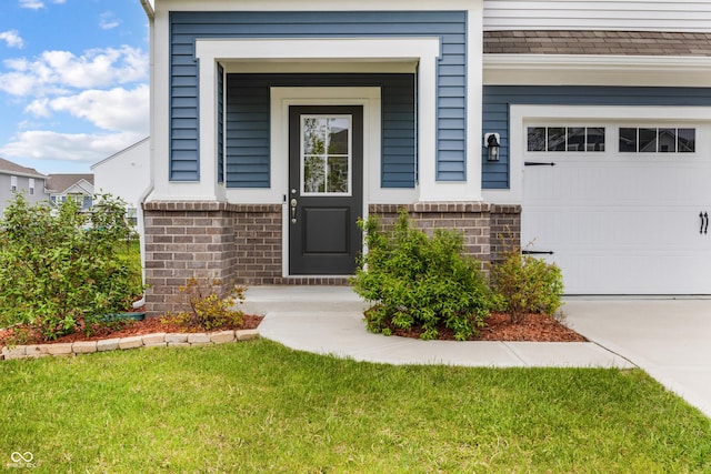 entrance to property with a lawn, brick siding, driveway, and a garage