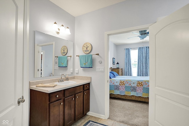 ensuite bathroom featuring vanity, tile patterned floors, a ceiling fan, and baseboards