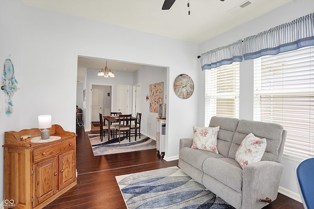 living room with ceiling fan, a chandelier, dark wood-type flooring, and baseboards