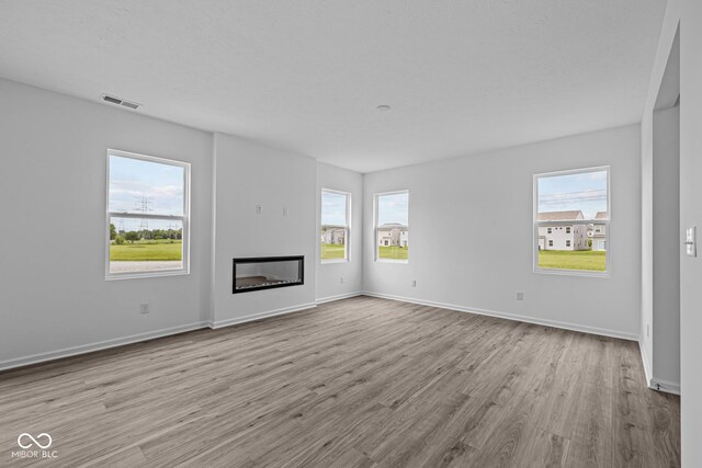 6219 Medina Spirit Dr, Indianapolis, IN 46237 - unfurnished living room featuring wood finished floors, plenty of natural light, and a glass covered fireplace