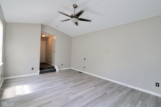 unfurnished room featuring a ceiling fan, light wood finished floors, lofted ceiling, and baseboards