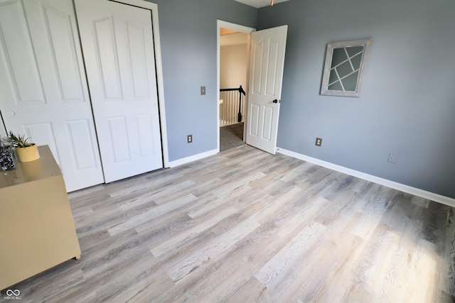 unfurnished bedroom with light wood-style flooring, baseboards, and a closet