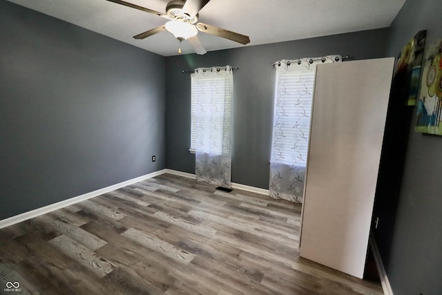 empty room featuring wood finished floors, ceiling fan, and baseboards