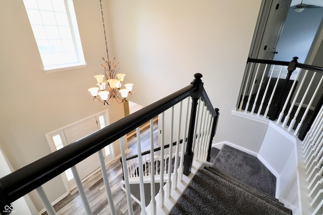 stairway with a chandelier, a towering ceiling, and baseboards