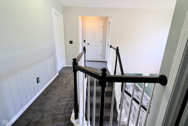 corridor with an upstairs landing, carpet floors, and baseboards