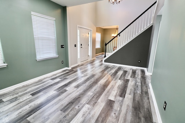 foyer entrance with a chandelier, stairs, wood finished floors, and baseboards