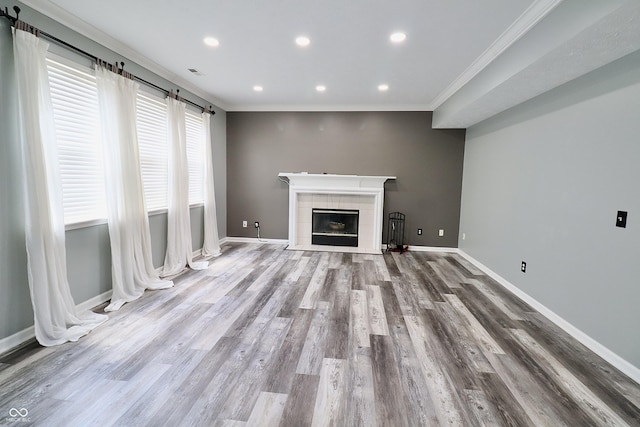 unfurnished living room with crown molding, baseboards, wood finished floors, recessed lighting, and a fireplace