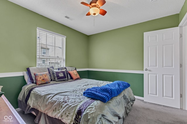 carpeted bedroom featuring ceiling fan, baseboards, and a textured ceiling