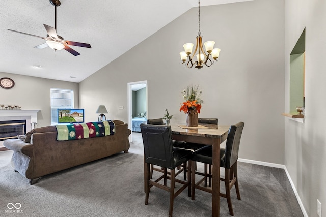 carpeted dining area with a chandelier, a glass covered fireplace, a ceiling fan, baseboards, and high vaulted ceiling