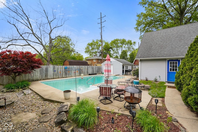 view of swimming pool with a patio, a fire pit, a fenced backyard, an outbuilding, and a fenced in pool