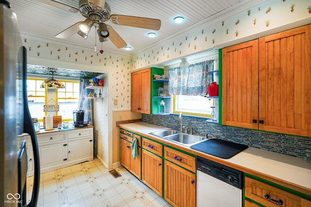 kitchen with a sink, freestanding refrigerator, ornamental molding, dishwasher, and ceiling fan
