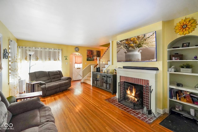 living room with stairway, a fireplace, and wood finished floors