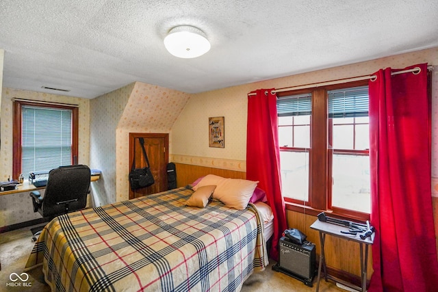 bedroom featuring wallpapered walls, a textured ceiling, wood walls, and wainscoting