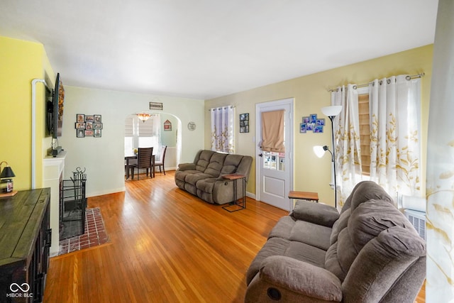 living area with arched walkways, baseboards, and wood finished floors