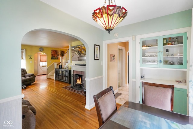 dining space featuring stairway, arched walkways, and wood finished floors
