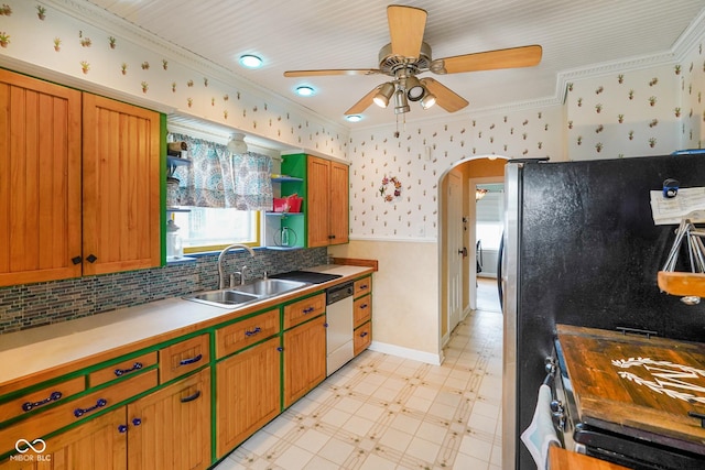 kitchen featuring a sink, light floors, dishwashing machine, arched walkways, and a ceiling fan
