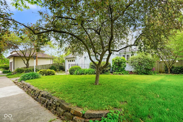 view of front of house featuring fence, a garage, and a front lawn