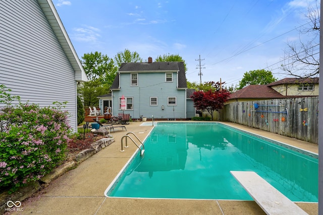 view of swimming pool featuring a diving board, a fenced in pool, a fenced backyard, and a patio