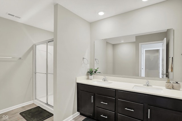 full bathroom featuring a shower stall, baseboards, a sink, and wood finished floors