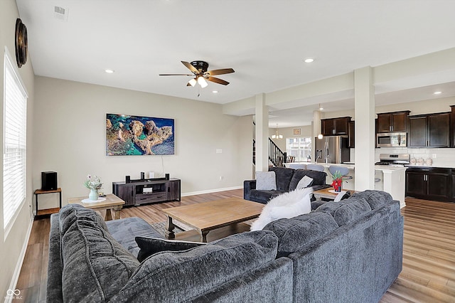 living area with stairway, light wood finished floors, and a ceiling fan