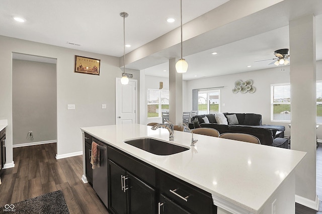 kitchen featuring a ceiling fan, dark cabinetry, dark wood-style flooring, a sink, and light countertops