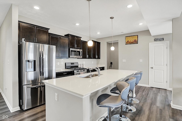 kitchen featuring baseboards, appliances with stainless steel finishes, a sink, and dark wood-type flooring