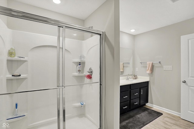 full bathroom featuring vanity, baseboards, a shower stall, and recessed lighting