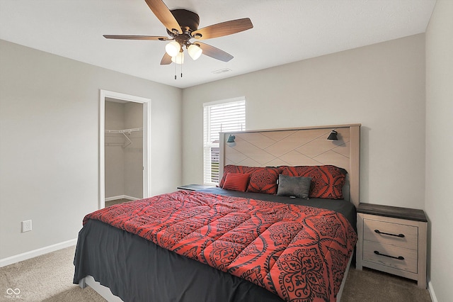 bedroom featuring a ceiling fan, baseboards, carpet flooring, visible vents, and a walk in closet