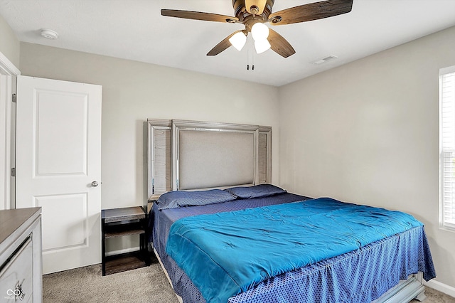 carpeted bedroom featuring baseboards, ceiling fan, multiple windows, and visible vents
