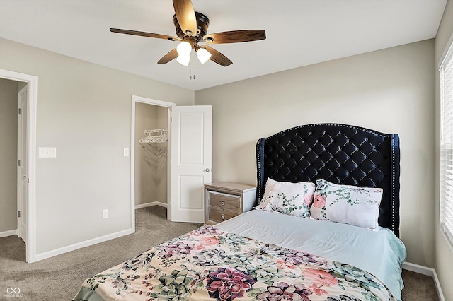 carpeted bedroom with a spacious closet, baseboards, and a ceiling fan