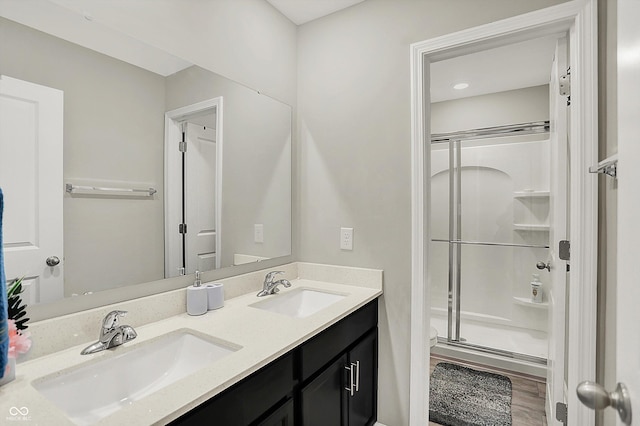 full bath featuring double vanity, wood finished floors, a shower stall, and a sink
