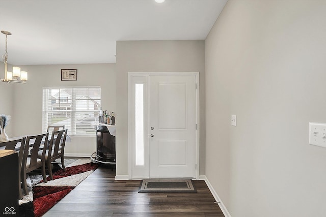 entrance foyer with a chandelier, baseboards, and dark wood finished floors
