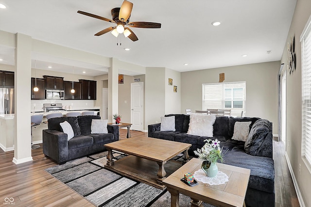 living area featuring a ceiling fan, light wood-style floors, recessed lighting, and baseboards