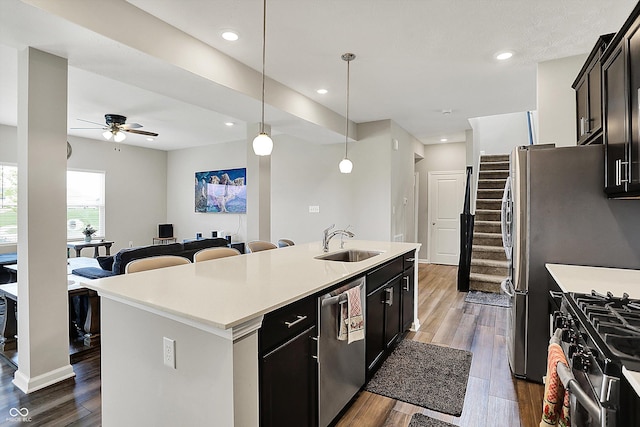 kitchen featuring a center island with sink, stainless steel appliances, dark wood-style flooring, and a sink