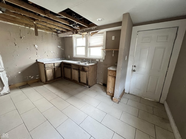 kitchen with brown cabinetry, light countertops, and a sink