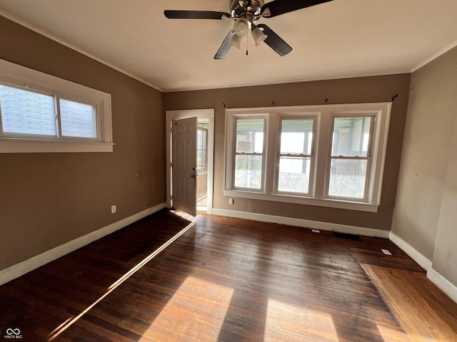 spare room with ornamental molding, plenty of natural light, baseboards, and wood finished floors