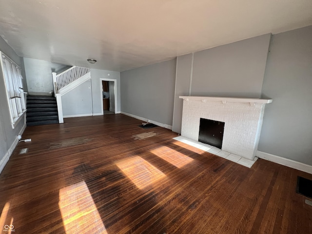 unfurnished living room featuring stairway, baseboards, a fireplace, and hardwood / wood-style floors