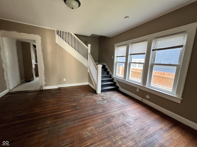 unfurnished living room with hardwood / wood-style floors, baseboards, a healthy amount of sunlight, and stairs