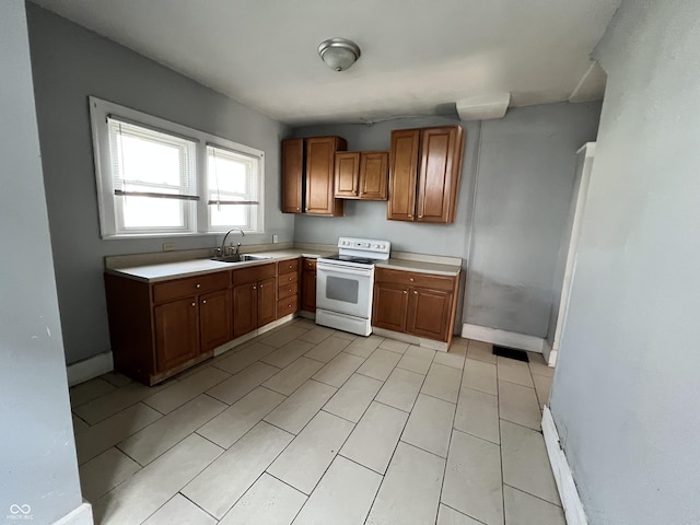 kitchen featuring a sink, white range with electric cooktop, brown cabinetry, baseboards, and light countertops