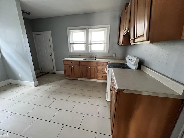kitchen with light tile patterned floors, brown cabinets, a sink, white electric stove, and light countertops
