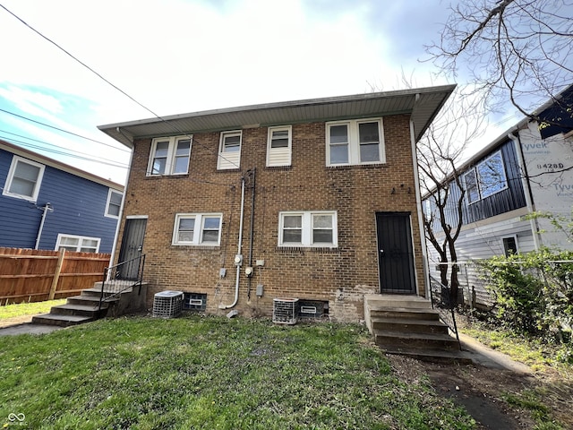 back of house featuring entry steps, fence, and brick siding
