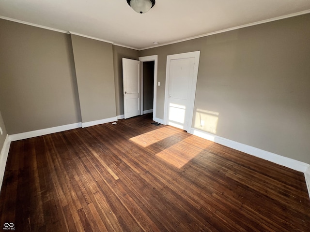 unfurnished bedroom with baseboards, crown molding, and dark wood-type flooring