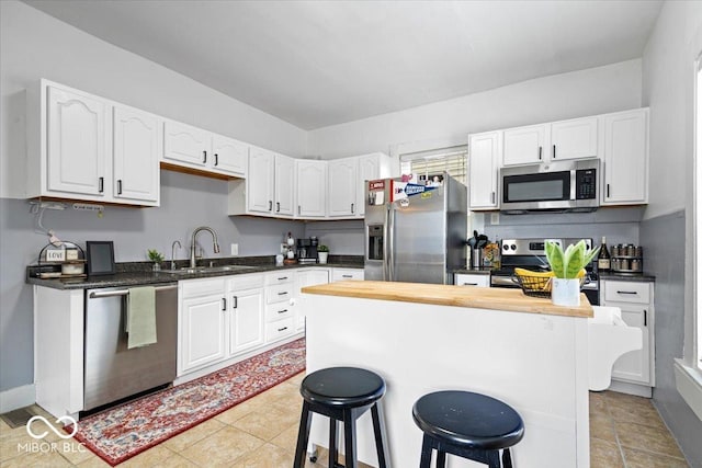925 S State Ave, Indianapolis, IN 46203 - kitchen featuring appliances with stainless steel finishes, a sink, white cabinets, and a kitchen breakfast bar